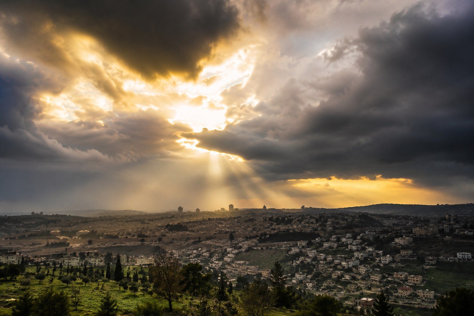 Sunbeams breaking through clouds over a city